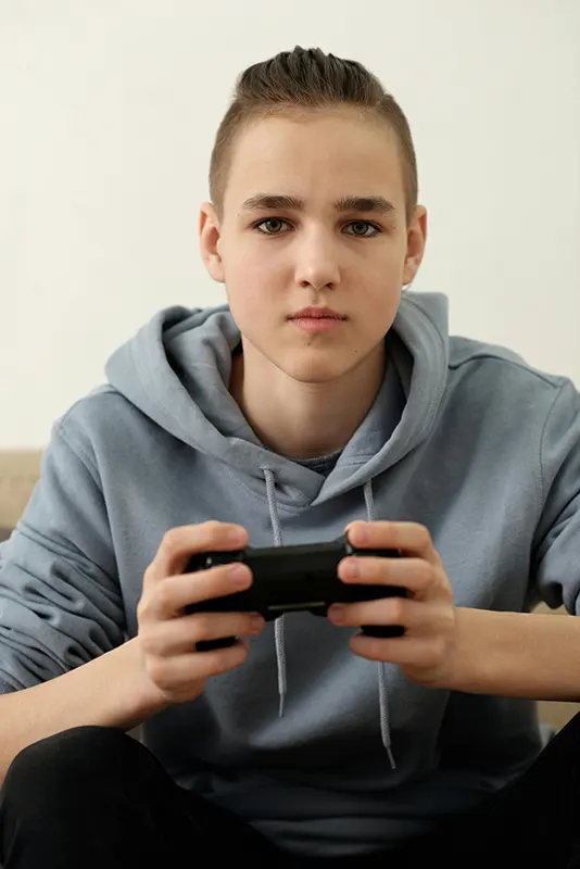 Boy wearing gray hoodie holding black remote controller